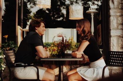 Younger couple smiling at each other across a bistro table